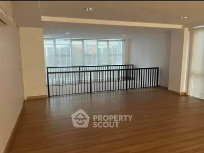 Spacious modern living area with wooden flooring and large windows.