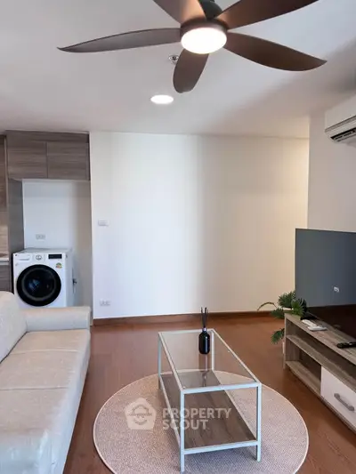 Modern living room with ceiling fan, washing machine, and stylish furniture in a cozy apartment.