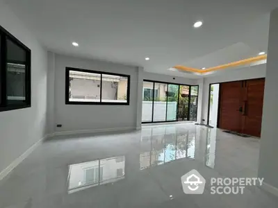 Spacious modern living room with large windows and glossy floors in a contemporary home.