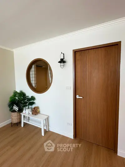Charming interior with wooden door, round mirror, and stylish decor in a cozy living space.