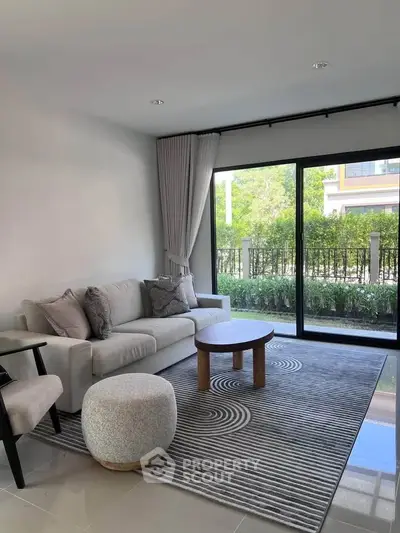 Modern living room with large window and stylish furniture in a bright, airy space.