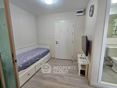 Compact bedroom with single bed and wall-mounted TV, adjacent to a bathroom.