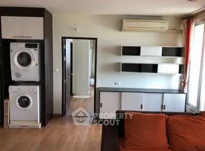 Modern living room with washer and dryer, air conditioning, and stylish shelving.