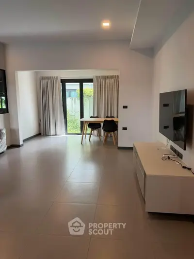 Spacious modern living room with large windows and minimalist decor, perfect for natural light lovers.
