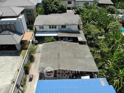 Aerial view of residential property with multiple buildings and lush greenery.