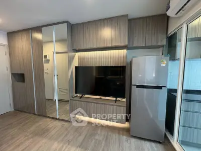 Modern living room with sleek wooden cabinetry and stainless steel fridge, perfect for contemporary living.