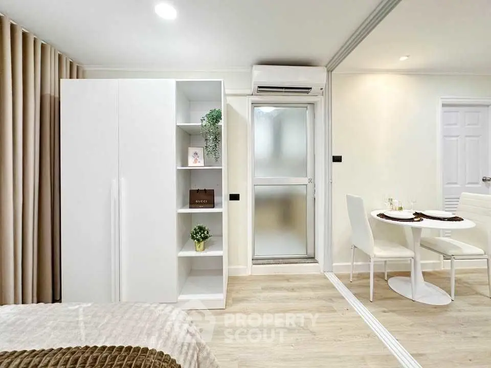 Modern bedroom with sleek white furniture and cozy dining area