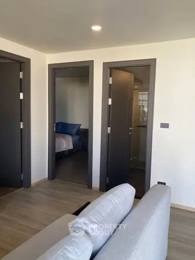 Modern apartment interior with cozy living room and view into bedroom and bathroom.