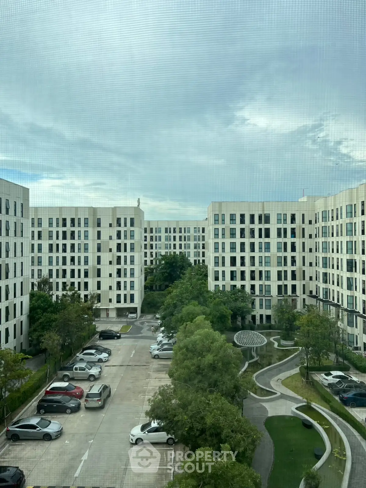 Modern apartment complex with lush greenery and ample parking space