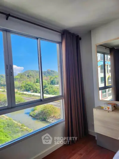 Bright bedroom with large window offering scenic green view