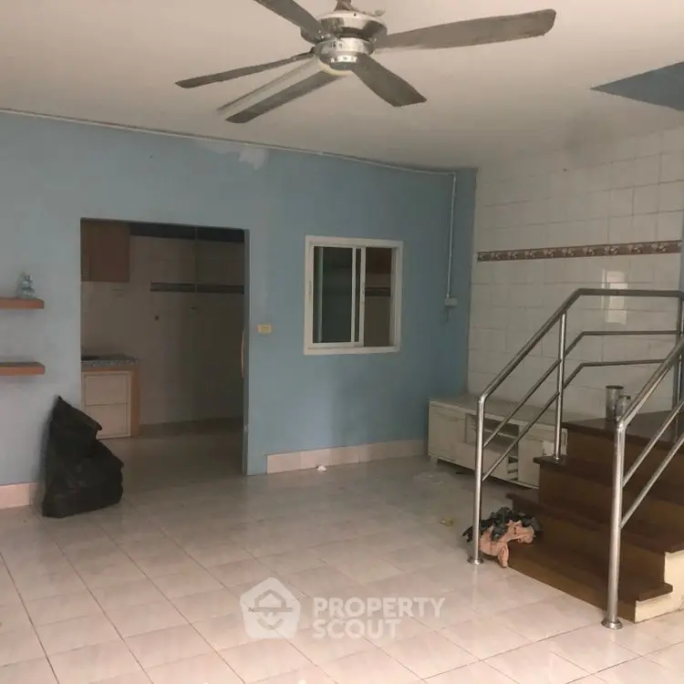 Spacious living area with ceiling fan and staircase in a modern home.