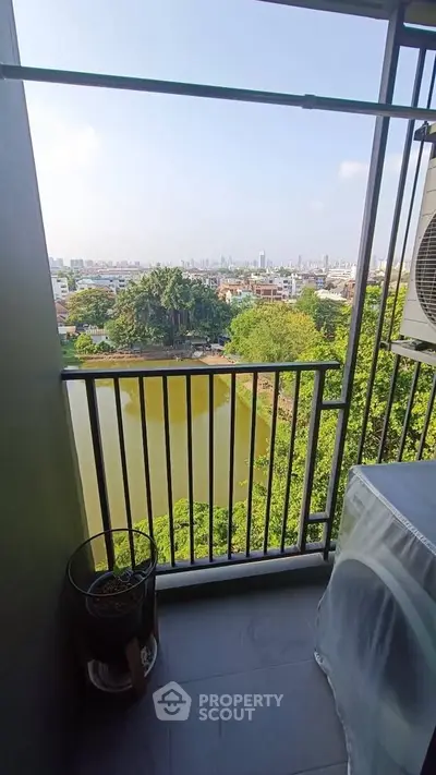 Stunning balcony view overlooking lush greenery and serene water body in urban setting.
