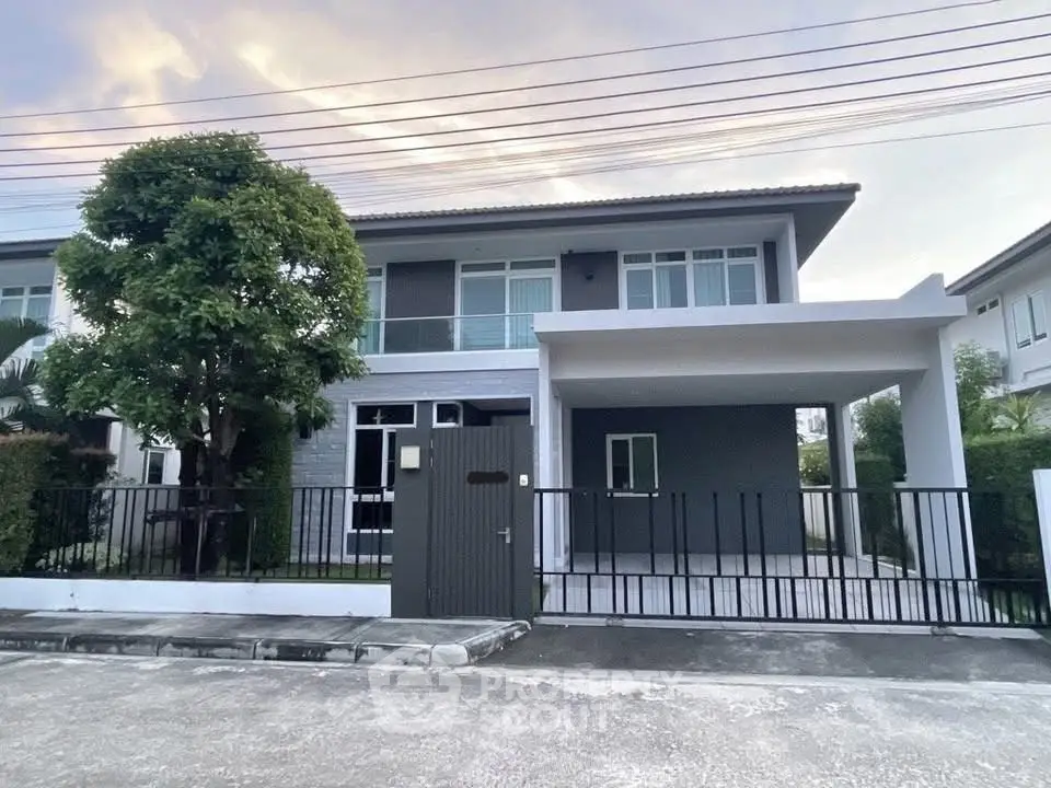 Modern two-story house with spacious driveway and lush greenery in a serene neighborhood.