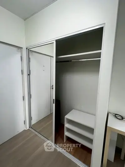 Spacious walk-in closet with sliding mirror doors and built-in shelving