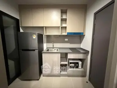 Modern compact kitchen with sleek cabinetry and stainless steel appliances in a stylish apartment.