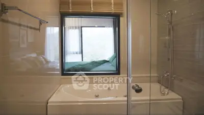 Luxurious bathroom with bathtub and window view into a cozy bedroom.