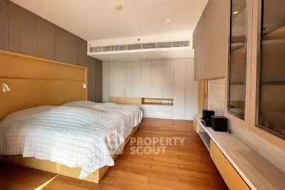 Spacious modern bedroom with wooden flooring and sleek built-in storage