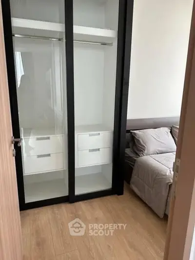 Modern bedroom with sleek glass wardrobe and cozy bed.