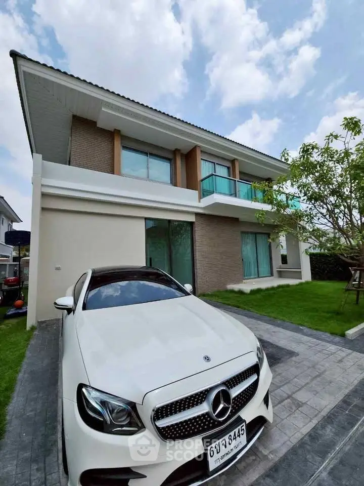 Modern two-story house with luxury car parked in driveway, showcasing contemporary architecture and lush lawn.