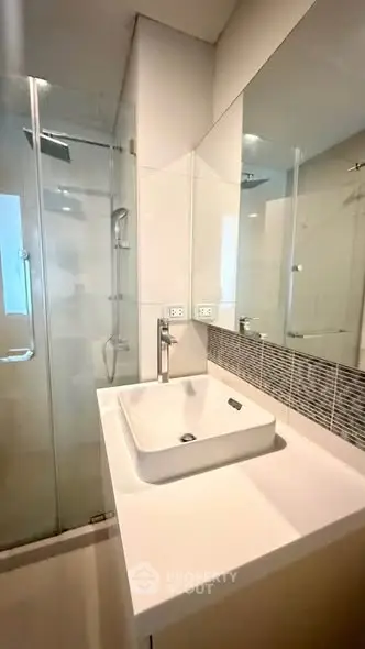Modern bathroom with sleek glass shower and stylish sink in contemporary apartment.