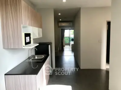 Modern kitchen with sleek cabinetry and open layout leading to a bright living area with balcony view.
