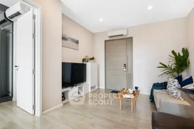 Modern living room with stylish decor and air conditioning, featuring a cozy sofa and flat-screen TV.