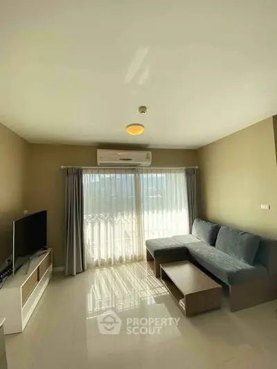 Bright living room with modern sofa, TV, and large window with curtains.