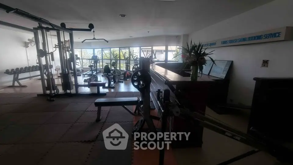 Spacious gym with modern equipment and large windows offering natural light.