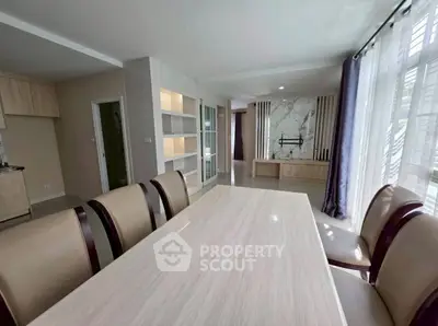 Spacious dining area with elegant table and chairs, adjacent to a modern living room with stylish decor.