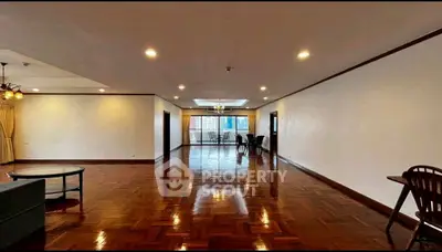 Spacious living room with polished wooden floors and city view balcony.