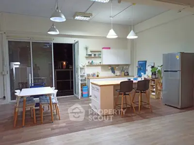 Spacious modern kitchen with island and dining area, featuring sleek appliances and stylish lighting.