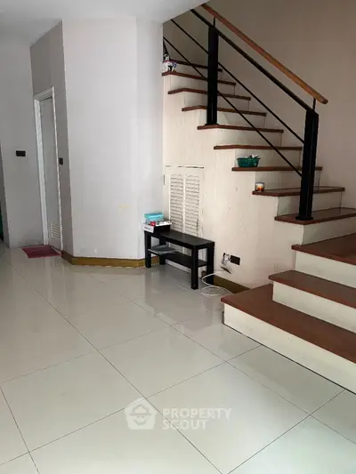 Modern staircase with sleek design in a spacious interior, featuring glossy tiled flooring and minimalist decor.