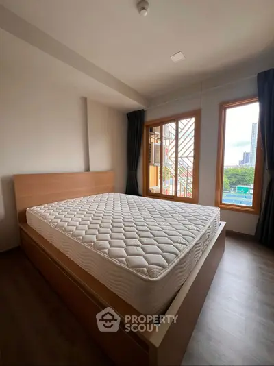 Spacious bedroom with large windows and modern wooden bed frame.