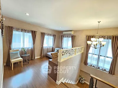 Elegant living room with stylish decor and natural light, featuring a cozy seating area and modern chandelier.