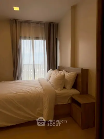 Cozy bedroom with modern wooden furniture and large window offering natural light.