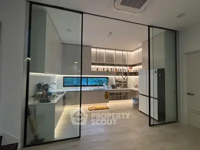 Modern kitchen with sleek cabinetry and large glass doors, featuring ambient lighting and spacious design.