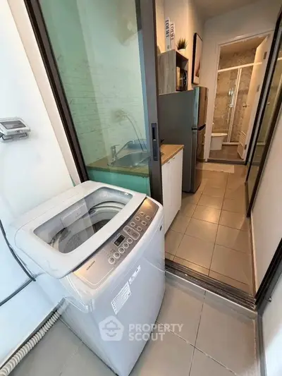 Compact apartment with modern washing machine and sleek bathroom design.