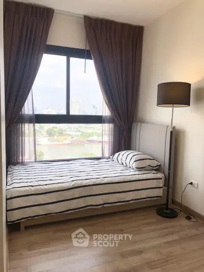 Cozy bedroom with city view, featuring a single bed and floor lamp, perfect for urban living.