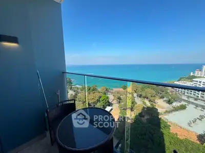 Stunning ocean view from a modern balcony with glass railing and cozy seating.