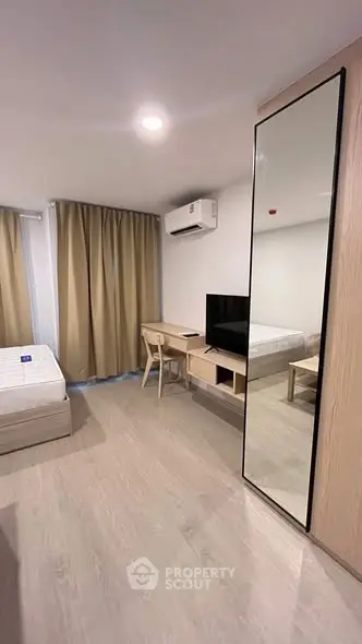 Modern bedroom with minimalist design, featuring a bed, desk, and large mirror.