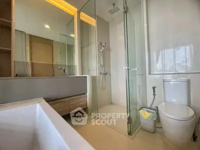 Modern bathroom with glass shower, bathtub, and sleek fixtures in a contemporary home.