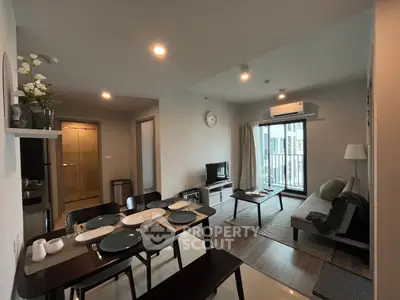 Modern open-plan living room with dining area and balcony access in a stylish apartment.