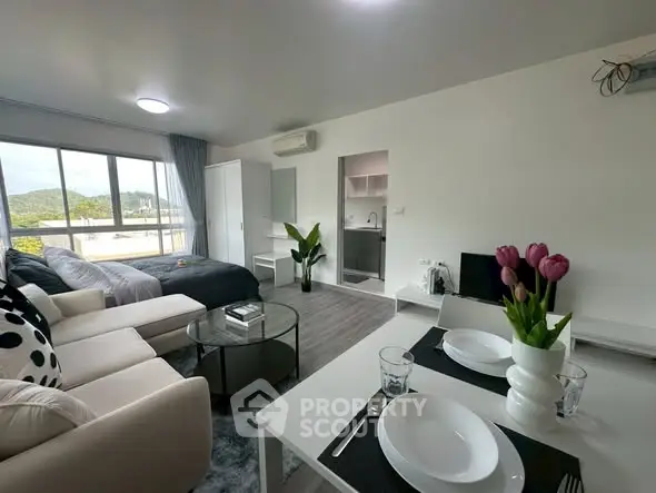 Modern open-plan living room with cozy seating and dining area, featuring large windows and stylish decor.