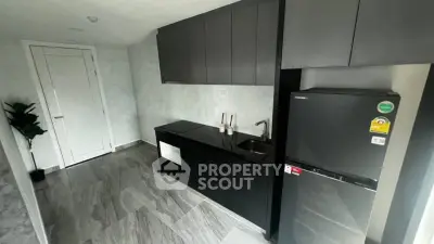Modern kitchen with sleek black cabinets and stainless steel fridge