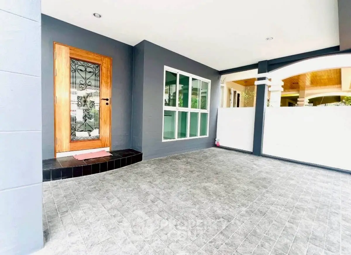 Modern entrance with elegant door and spacious tiled patio area.
