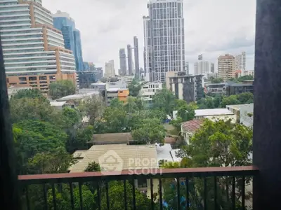 Stunning urban view from a high-rise building balcony overlooking cityscape and lush greenery.