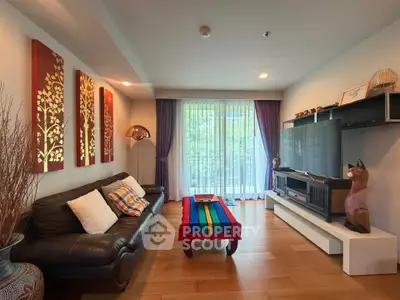Stylish living room with modern decor and large TV, featuring elegant wooden flooring and vibrant wall art.