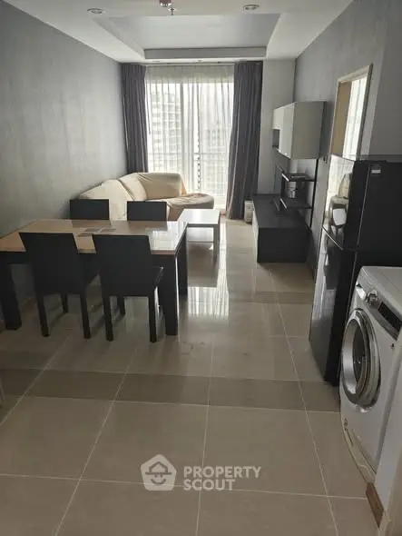 Modern living room with sleek furniture and appliances, featuring a washing machine and dining area.