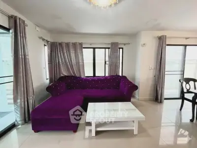 Spacious living room with elegant purple sofa and natural light