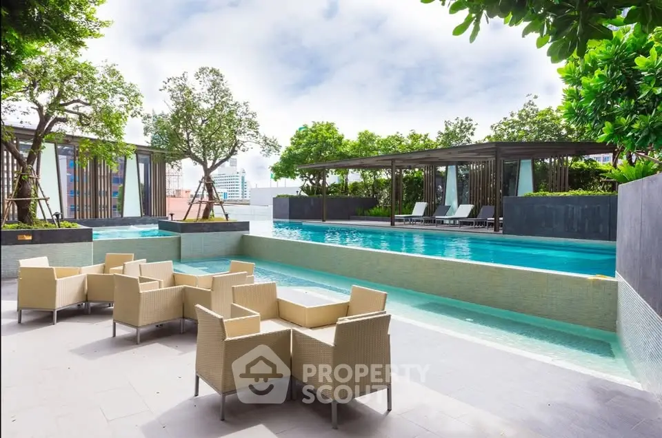 Luxurious rooftop pool area with modern seating and lush greenery in a high-rise building.